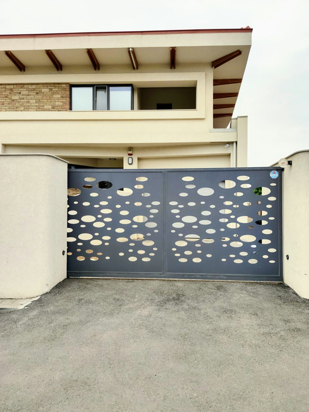 Portón corredizo metálico con diseño perforado en una casa de su comuna